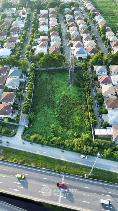 Aerial view of residential neighborhood with vacant green lot and surrounding houses.