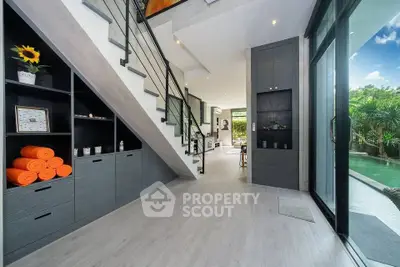 Modern open-plan living space with pool view and stylish staircase