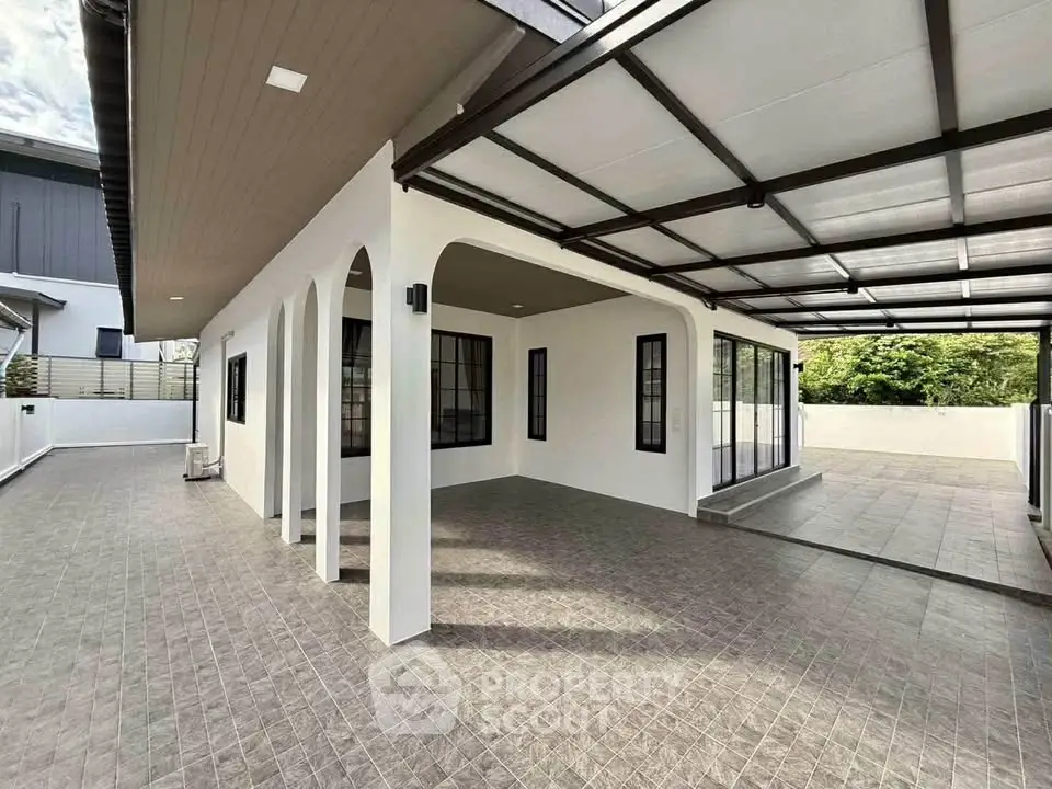 Modern home exterior with spacious tiled patio and sleek black-framed windows.
