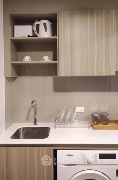 Modern kitchen with sleek cabinetry, washing machine, and stylish countertop in compact layout.