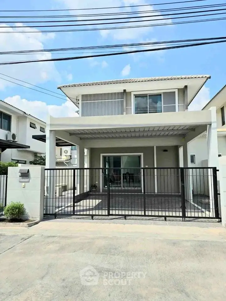 Modern two-story house with gated entrance and spacious driveway in suburban neighborhood.