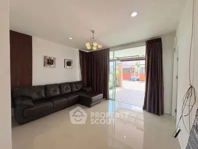 Spacious living room with modern decor and large glass doors leading to outdoor area.