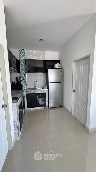 Modern kitchen with sleek appliances and stylish backsplash in a contemporary apartment.