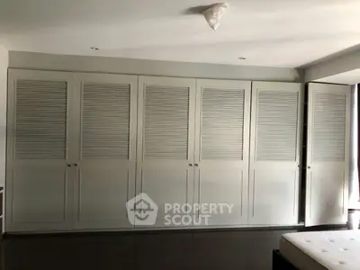 Spacious bedroom with large built-in wardrobe and sleek modern design.