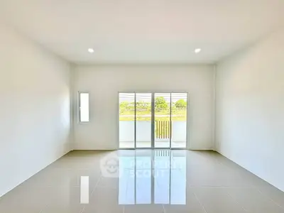 Spacious and bright living room with large windows and glossy tiled floor, offering a serene view.