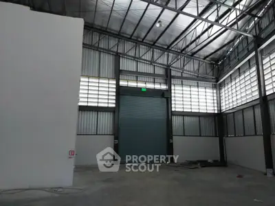 Spacious industrial warehouse with high ceilings and large roller door access.