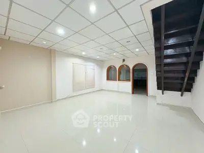 Spacious open living room with modern ceiling and staircase, ideal for family gatherings.