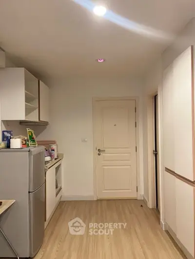 Modern kitchen with sleek appliances and wooden flooring in a cozy apartment.