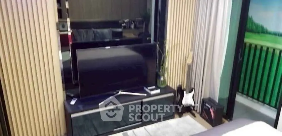 Modern living room with TV and balcony view, stylish decor and natural light.