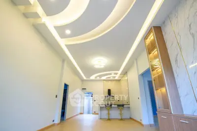 Spacious modern living room with stylish ceiling design and open kitchen layout.