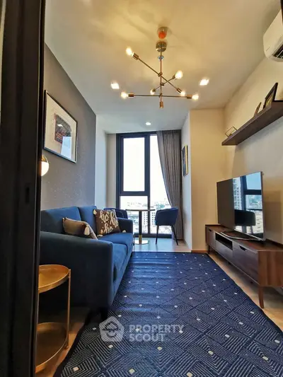 Modern living room with stylish decor and city view, featuring a blue sofa and contemporary lighting.
