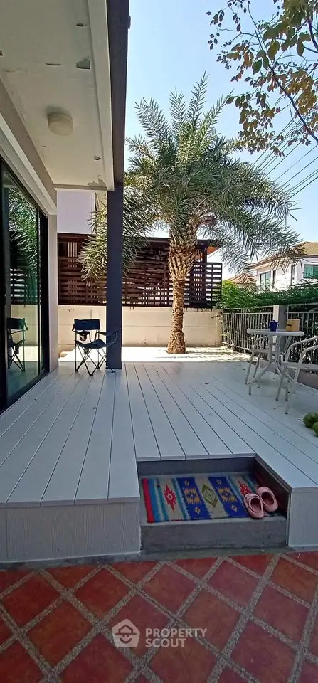 Charming outdoor patio with modern decking and lush palm tree, perfect for relaxation and entertaining.