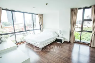 Spacious bedroom with large windows offering stunning city views and natural light.