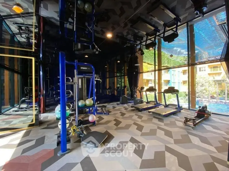 Modern gym with state-of-the-art equipment and large windows overlooking a pool area.