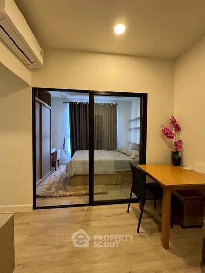 Modern apartment interior with glass partition separating bedroom and dining area, featuring elegant decor.