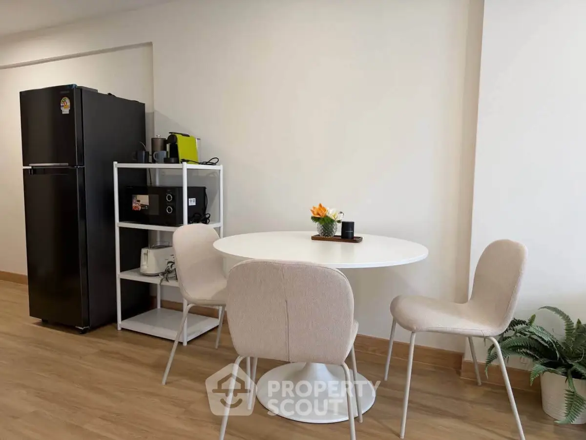 Modern dining area with sleek black fridge and stylish round table in a cozy apartment.