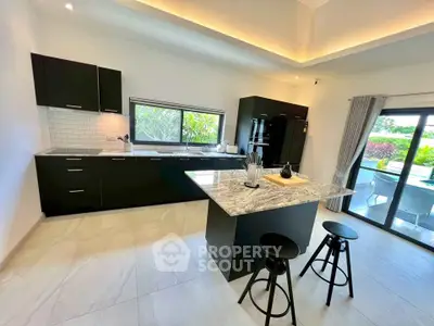 Modern kitchen with island, black cabinets, and garden view.