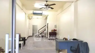 Spacious interior with high ceiling and ceiling fan, ideal for versatile use.