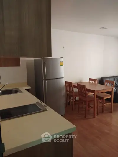Modern kitchen with dining area and stainless steel fridge in cozy apartment