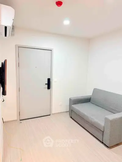 Modern minimalist living room with sleek gray sofa and wall-mounted TV, perfect for cozy relaxation.