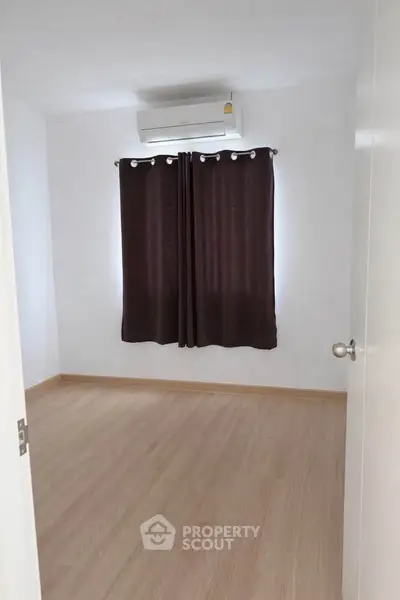 Spacious empty room with wooden flooring and air conditioning, perfect for customization.