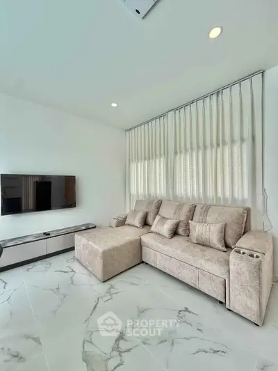 Modern living room with elegant marble flooring and cozy beige sofa, featuring a wall-mounted flat-screen TV.