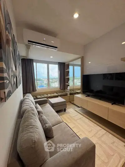 Modern living room with large window and stylish decor, featuring a comfortable sofa and entertainment center.