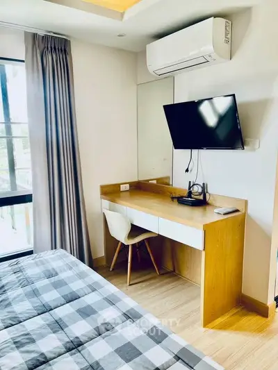 Modern bedroom with stylish desk, wall-mounted TV, and air conditioning unit.