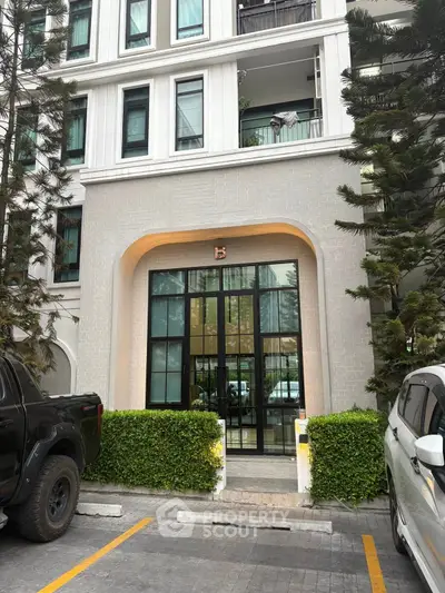 Elegant building entrance with modern design and lush greenery, perfect for urban living.