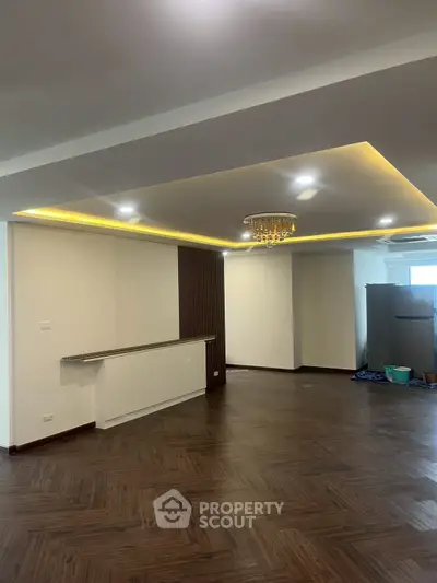 Spacious modern living room with elegant ceiling lighting and wooden flooring.