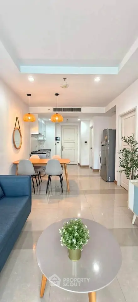 Modern open-plan living room with stylish furniture and kitchen area, featuring pendant lights and a cozy ambiance.