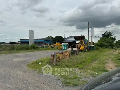Industrial property with heavy machinery and open land under cloudy sky