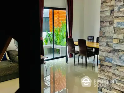 Modern dining area with sleek furniture and garden view through glass doors.