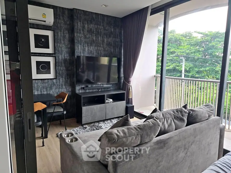 Modern living room with stylish decor and large balcony overlooking greenery.