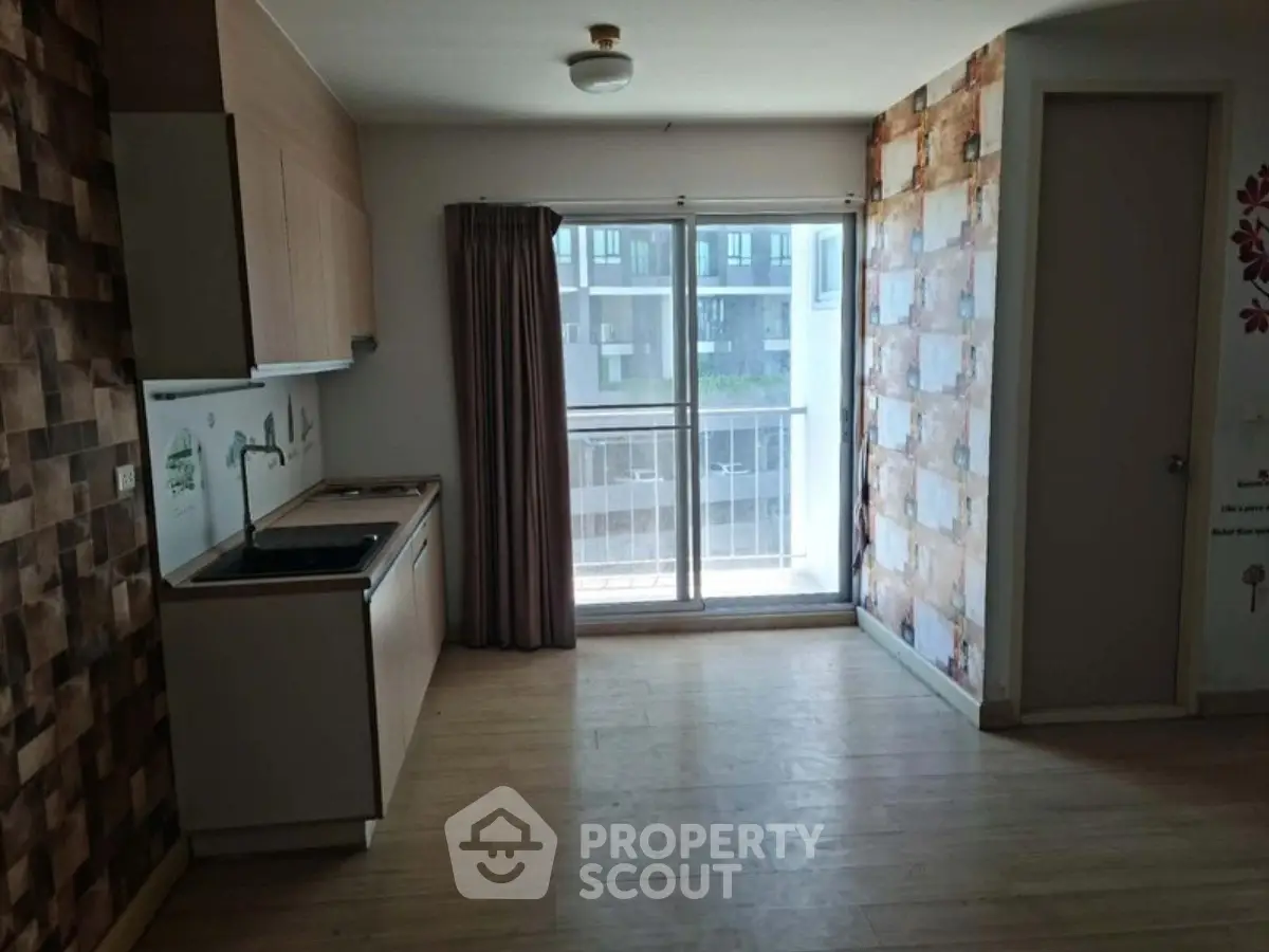 Cozy apartment with compact kitchen and balcony view, perfect for urban living.