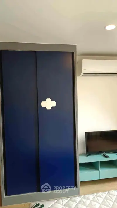 Modern bedroom with sleek blue wardrobe and wall-mounted TV unit