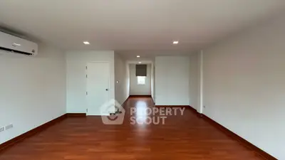 Spacious empty room with wooden flooring and air conditioning, perfect for customization.