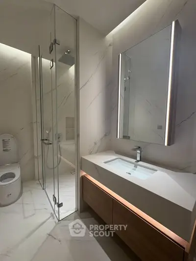 Luxurious modern bathroom with sleek glass shower and elegant vanity lighting.