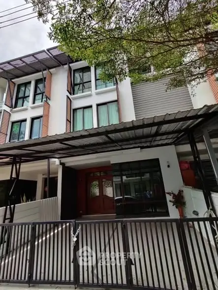 Modern townhouse exterior with gated entrance and covered parking area.