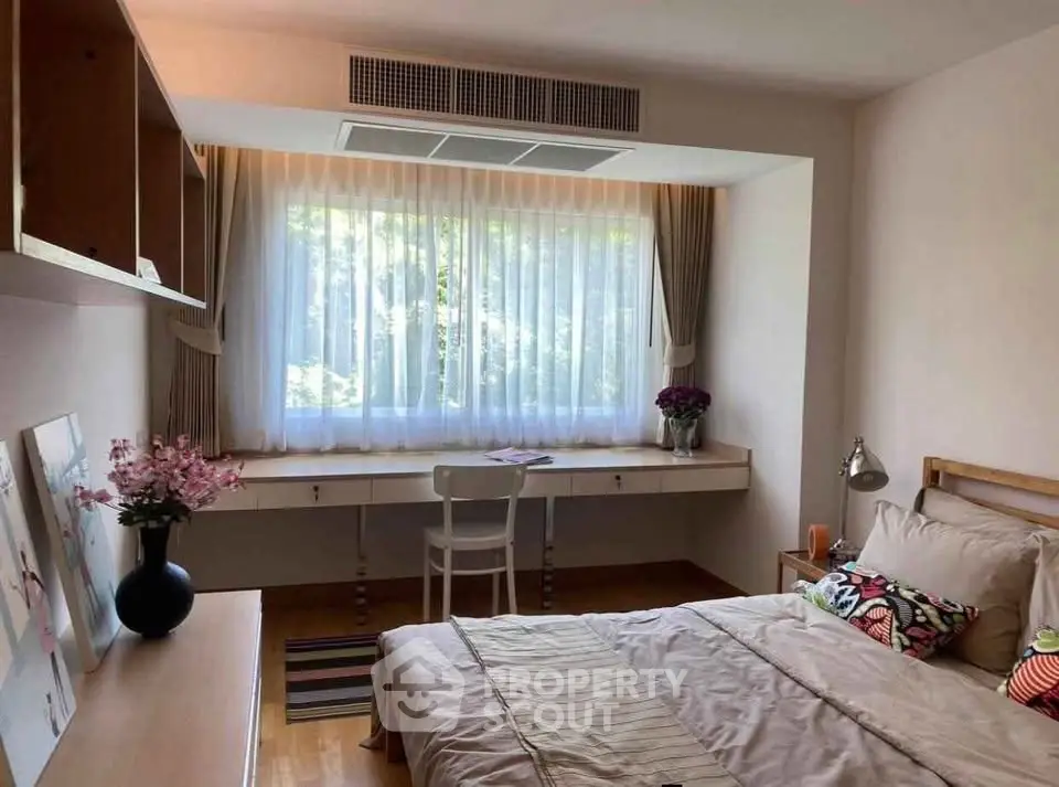 Cozy bedroom with large window and stylish decor, perfect for relaxation and comfort.