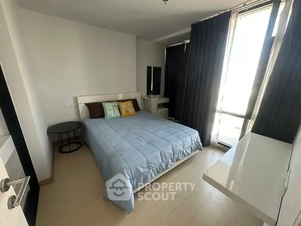 Modern bedroom with large window and stylish decor in a contemporary apartment.