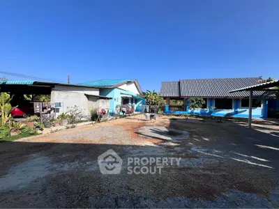 Charming rural property with spacious yard and traditional architecture under clear blue sky.