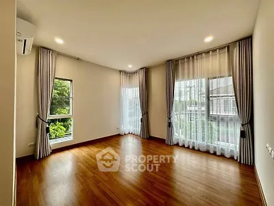 Spacious corner unit with large windows and elegant curtains, featuring beautiful hardwood floors and abundant natural light.