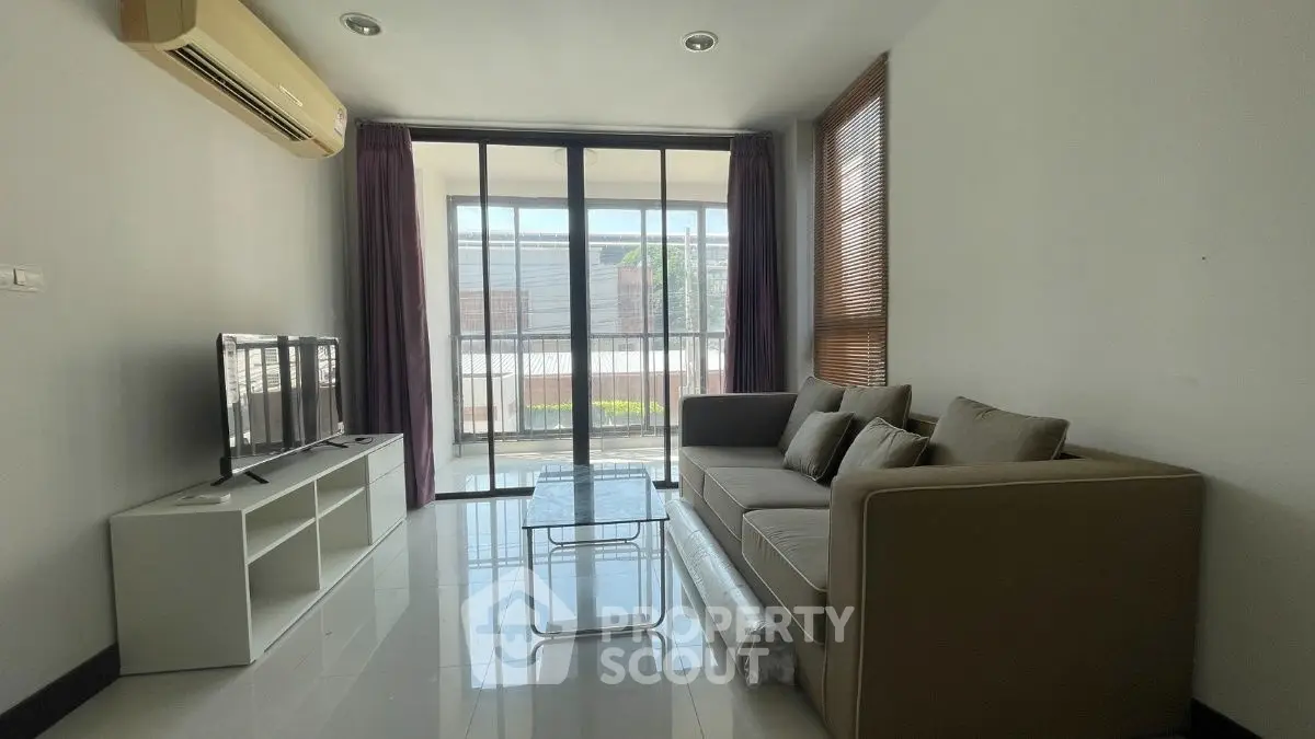 Modern living room with large windows and sleek furniture in a bright apartment.