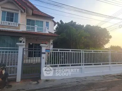Charming two-story house with a gated front yard and lush greenery, perfect for family living.