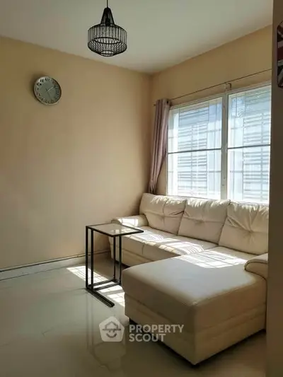 Bright living room with cozy white sectional sofa and natural light from large windows.