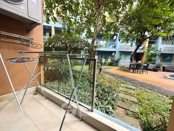 Charming garden view from a cozy balcony in a modern apartment complex.