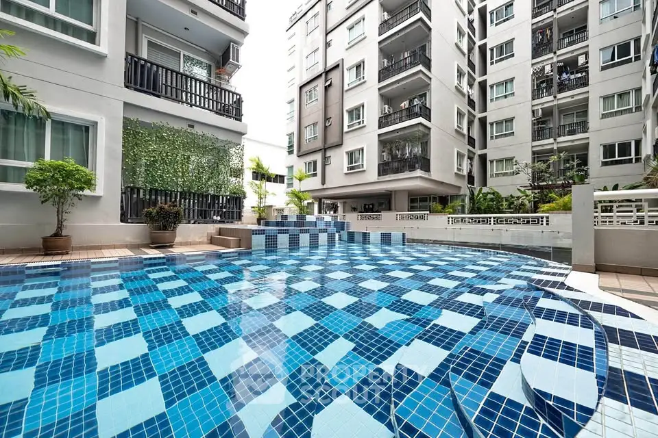 Modern apartment complex with stylish outdoor pool and lush greenery.