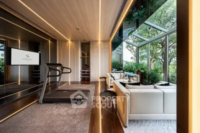 Luxurious home gym with treadmill and elegant seating area overlooking lush garden views.