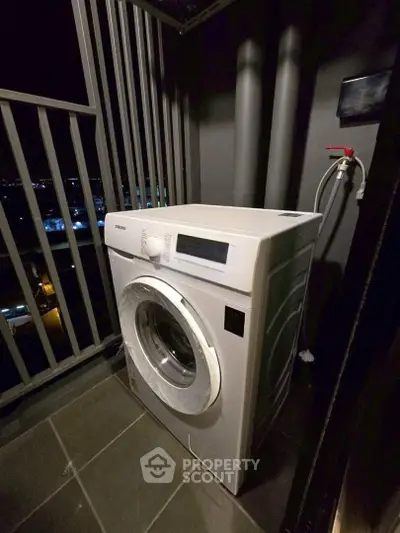 Modern washing machine on a balcony with city night view, perfect for urban living convenience.